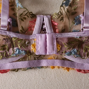 Detailed close-up of floral embroidery on sheer mesh purple bra with adjustable straps