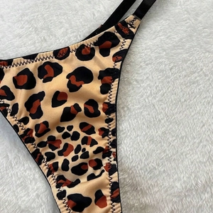 Detail of leopard print lingerie with black zigzag stitching on soft white faux fur