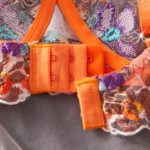 Detailed close-up of vibrant orange lace bra with multicolor floral embroidery and back closure