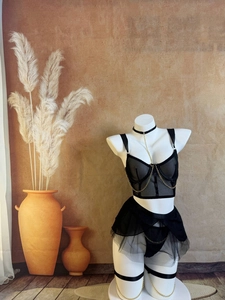 Détail d'un ensemble de lingerie en maille noire avec chaînes dorées et sangles décoratives