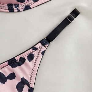Close-up of pink leopard print lingerie featuring adjustable black straps and silver buckles