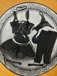 Détail d'un ensemble de lingerie en résille noire avec chaînes dorées et nuisette sheer