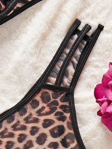 Detail view of sheer leopard print lace fabric with thin straps and black trim