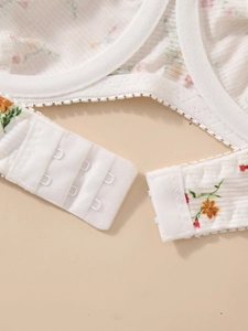 Detail of white floral bra back closure featuring three-row hook and eye fastener