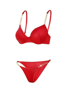 Détail d'un ensemble de lingerie en satin rouge avec chaînes dorées sur fond blanc