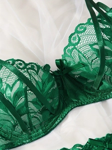 Dettaglio in pizzo floreale verde scuro e fiocco di seta su lingerie raffinata
