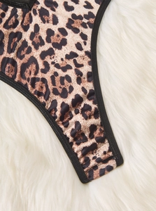 Close-up of leopard print bodysuit fabric with black elastic trim on plush background