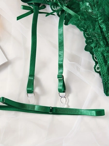 Vista macro dettagliata della lingerie in pizzo smeraldo con nastri di raso e fibbie argento
