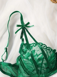 Dettaglio di lingerie in pizzo verde scuro con motivi a foglia e fiocco in seta