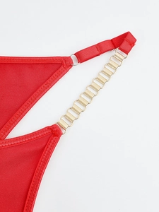 Détail du soutien-gorge en maille rouge avec chaînes métalliques dorées et tissu élastique