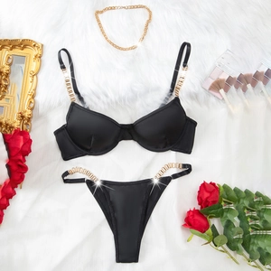 Ensemble lingerie noir en maille avec chaînes dorées élégantes sur fond en peluche blanc