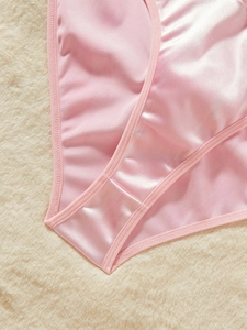Détail de lingerie en satin rose avec texture lisse et coutures fines sur fond en peluche