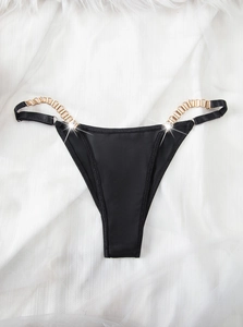 Détail du string en satin noir avec chaînes dorées élégantes et tissu soyeux lisse