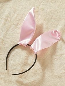 Gros plan d'un serre-tête oreilles de lapin en satin rose sur fond en fausse fourrure