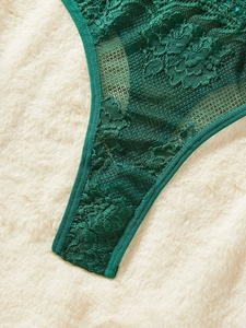 Detail of dark green lace panties featuring delicate floral embroidery and sheer mesh fabric