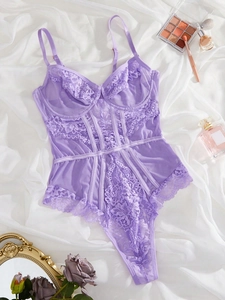 Flat lay of pink lace teddy lingerie with floral details and decorative beauty props