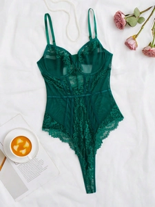 Detailed close-up of dark green floral lace and sheer mesh stitching on a slim teddy bodysuit