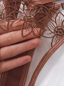 Detailed embroidery on sheer brown mesh fabric with floral patterns and strap detail