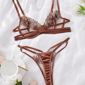Lace embroidery lingerie set with strappy bra and thong on white satin background