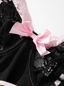 Detail of black lace bodysuit featuring a pink satin bow and delicate lace trim accents