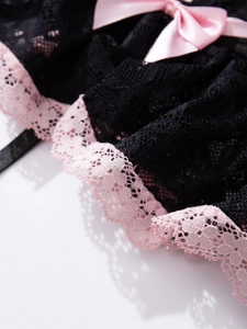 Detailed close-up of black floral lace bodysuit with pink ribbon and scalloped trim