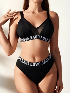 Detail of black V-neck lingerie set featuring mesh panels and LOVE lettered elastic band