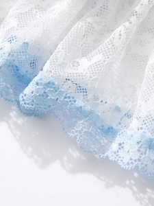 Detailed macro view of white and light blue floral lace fabric with layered pleats