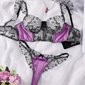 Flat lay of a purple satin and black lace lingerie set with elegant pearl accents