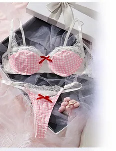 Detailed flat lay of pink plaid lingerie set with lace and red bows on a white gift box