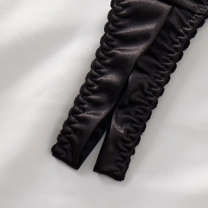 Detail of black satin lingerie with elastic ruffled edges and soft silky texture