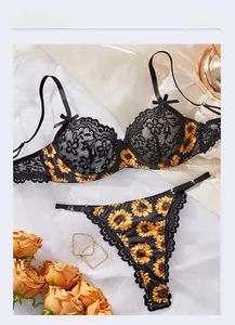 Detailed flat lay of black lace sunflower embroidery lingerie set on white silk fabric