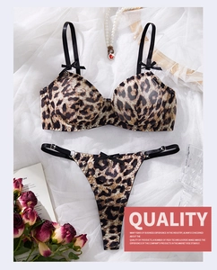 Flat lay detail of leopard print lace bra set with satin bows and pearl accessories