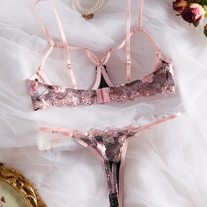 Dettaglio del ricamo floreale e design con cinturini su un set di lingerie in pizzo francese rosa