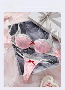 Detailed flat lay of pink gingham lingerie set with delicate white lace and red bows