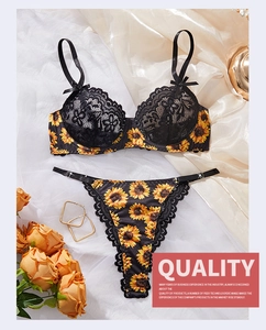Detailed flat lay of black lace sexy lingerie set with sunflower embroidery and yellow roses