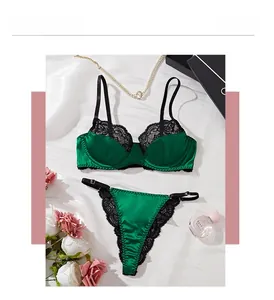 Flat lay of emerald green satin and black lace sexy bra set with elegant accessories