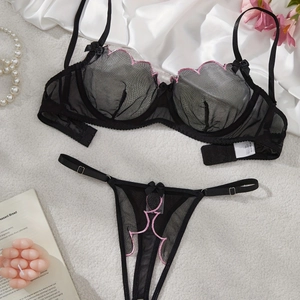 Detail of black mesh lingerie set with pink embroidery and floral lace on plush rug