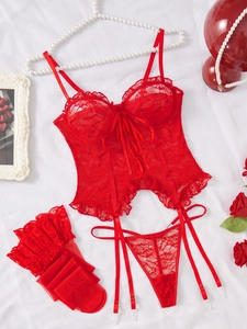 Flat lay of red lace lingerie set with garters, stockings and bow details on white fabric