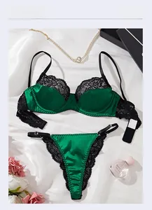Flat lay of dark green satin bra and lace thong set with luxury accessories
