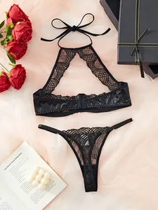 Flat lay of black lace lingerie set with halter neck top and thong near red roses