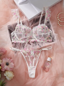 Detail of white mesh lingerie set with floral embroidery and ruffled straps decoration