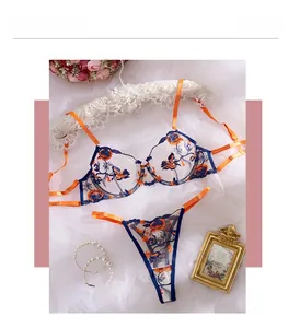 Detailed view of floral embroidery on sheer mesh lingerie set with vibrant orange straps