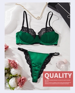 Detailed flat lay of dark green lace bra set on silk background with luxury props