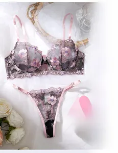Detail view of lace lingerie set with floral embroidery and pink bow on white fabric