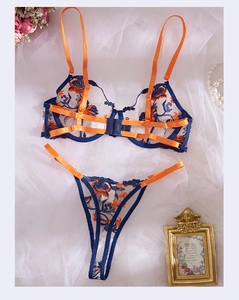 Detail of floral embroidery on two-piece sexy lingerie set with orange and blue contrast straps