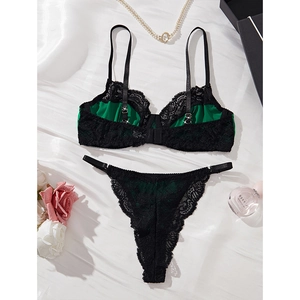 Elegant dark green and black lace lingerie set displayed on silk with luxury accessories