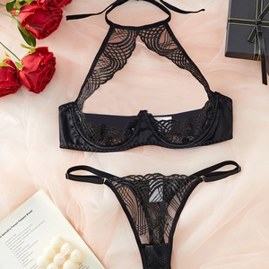 Sexy black lace lingerie set with halter neck bra and matching thong on a pink background