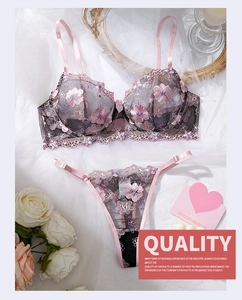 Detailed close-up of pink and black lace lingerie set with floral embroidery on white silk