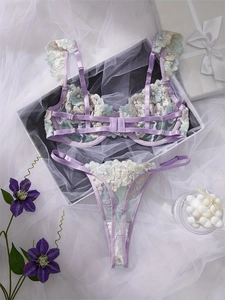 Flat lay of lavender lingerie set with floral embroidery and ruffled straps on silk