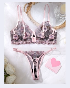 Detailed view of black lace lingerie set with pink floral embroidery on white gauze